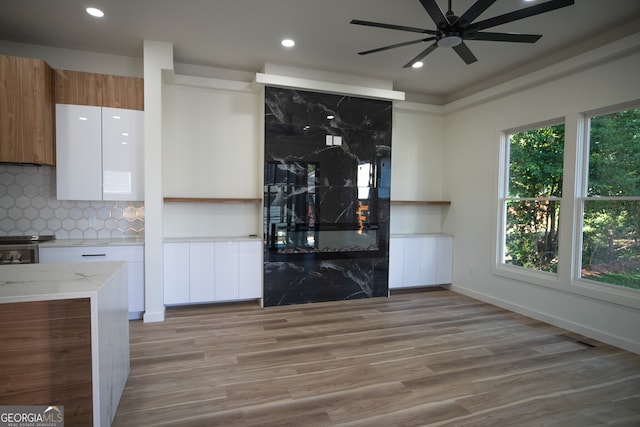 bar featuring decorative backsplash, white cabinets, ceiling fan, light hardwood / wood-style flooring, and electric range