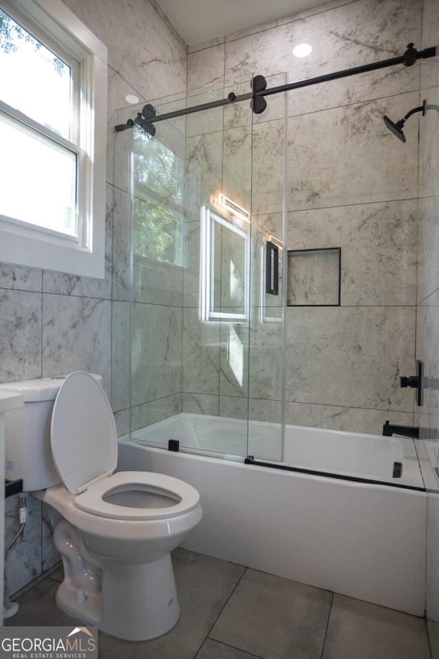 bathroom featuring enclosed tub / shower combo, tile walls, toilet, and tile patterned floors