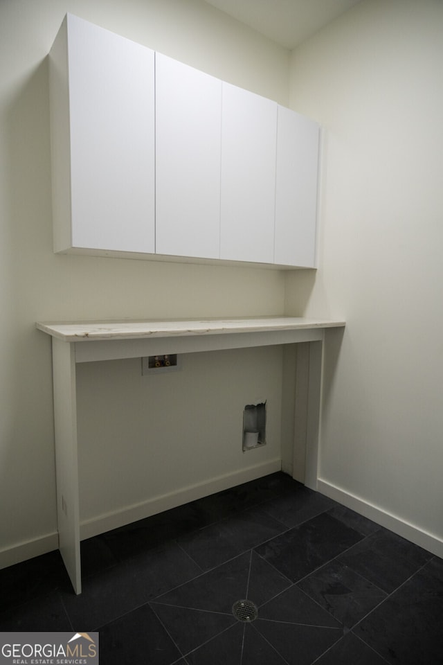 clothes washing area featuring hookup for a washing machine, dark tile patterned flooring, and cabinets