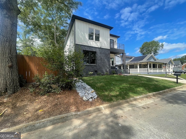 view of front of property featuring a balcony and a front yard