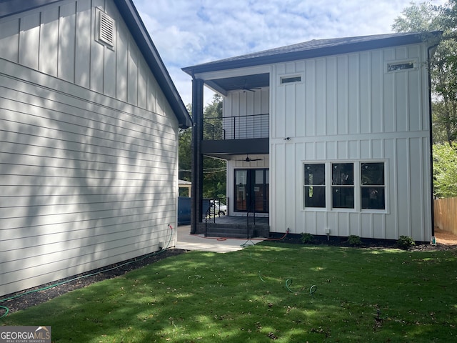 rear view of property featuring a patio, a balcony, and a yard