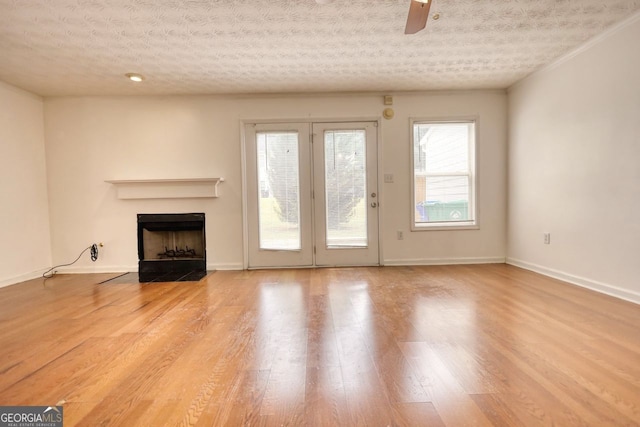 unfurnished living room featuring ceiling fan, a textured ceiling, and light wood-type flooring