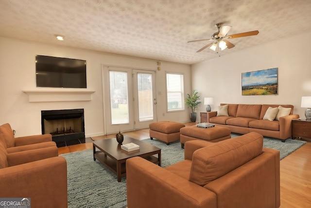 living room featuring ceiling fan, a textured ceiling, and hardwood / wood-style floors