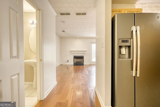 corridor with light hardwood / wood-style flooring and crown molding