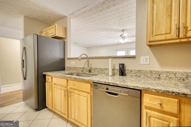 kitchen with ceiling fan, stainless steel appliances, light stone counters, and sink