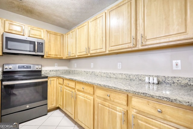 kitchen featuring light brown cabinetry, appliances with stainless steel finishes, light stone countertops, and light tile patterned floors