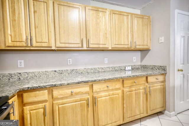 kitchen featuring light stone counters, stove, light brown cabinetry, and light tile patterned flooring