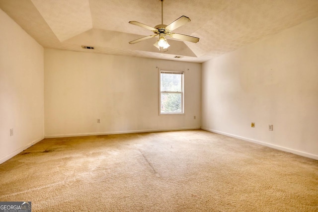 empty room featuring ceiling fan, a textured ceiling, a raised ceiling, and carpet