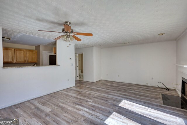 spare room with a textured ceiling, ceiling fan, and light colored carpet