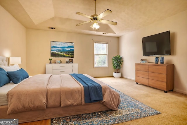 bedroom with ceiling fan, a tray ceiling, and light carpet