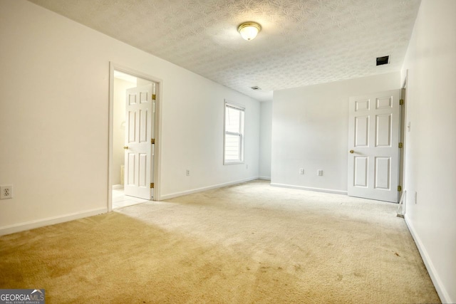 carpeted empty room with a textured ceiling