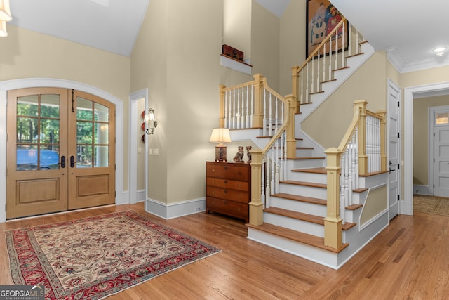 entrance foyer featuring crown molding, lofted ceiling, french doors, and hardwood / wood-style flooring