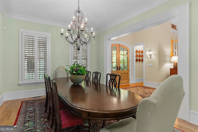 dining area with wood-type flooring, crown molding, a chandelier, and french doors