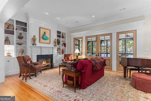 living room with light wood-type flooring, built in shelves, and crown molding