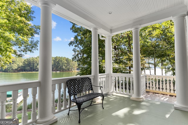 exterior space with ornate columns, a water view, and a healthy amount of sunlight