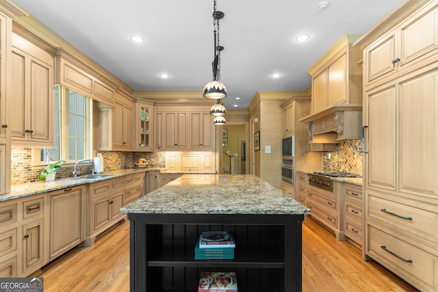 kitchen featuring stainless steel gas cooktop, light hardwood / wood-style floors, a kitchen island, and decorative light fixtures