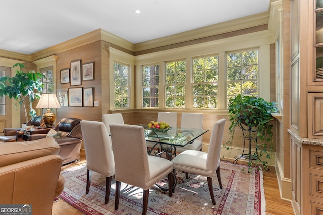 dining area with a healthy amount of sunlight, ornamental molding, and light hardwood / wood-style flooring