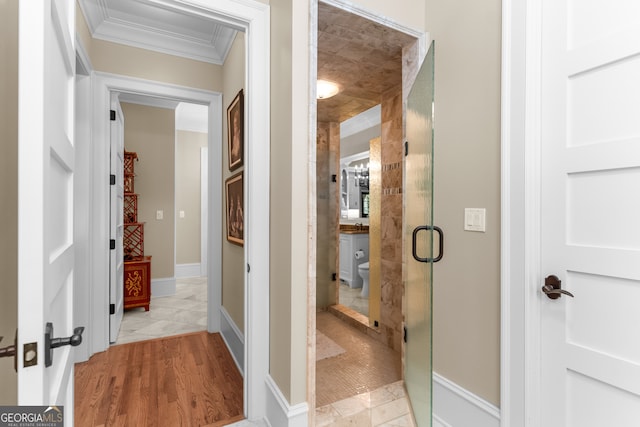 hall with ornamental molding and light hardwood / wood-style floors