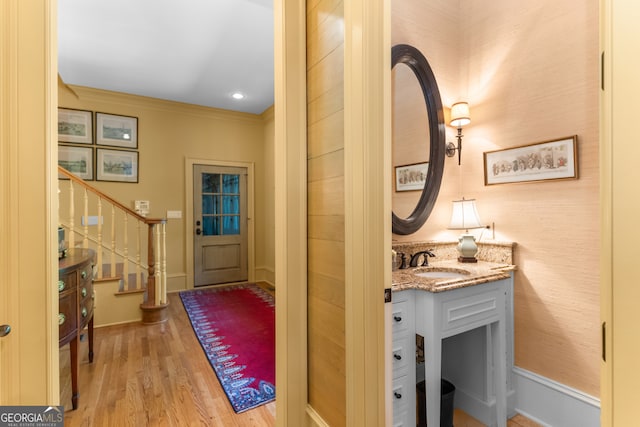 interior space with light wood-type flooring, crown molding, and sink