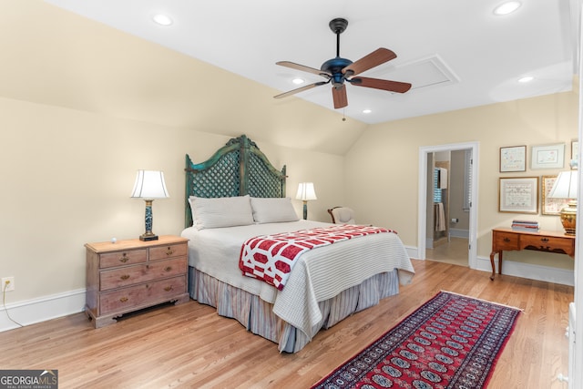 bedroom featuring light hardwood / wood-style floors, vaulted ceiling, ceiling fan, and ensuite bathroom