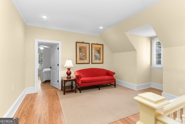 living area featuring ceiling fan, light wood-type flooring, ornamental molding, and lofted ceiling