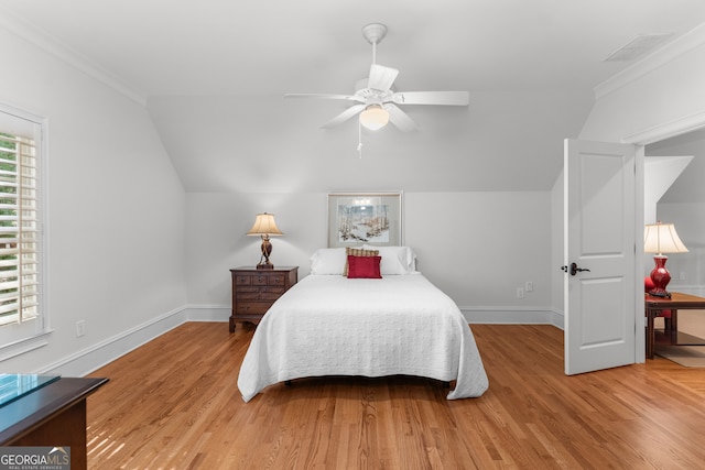 bedroom featuring light wood-type flooring, crown molding, lofted ceiling, and ceiling fan