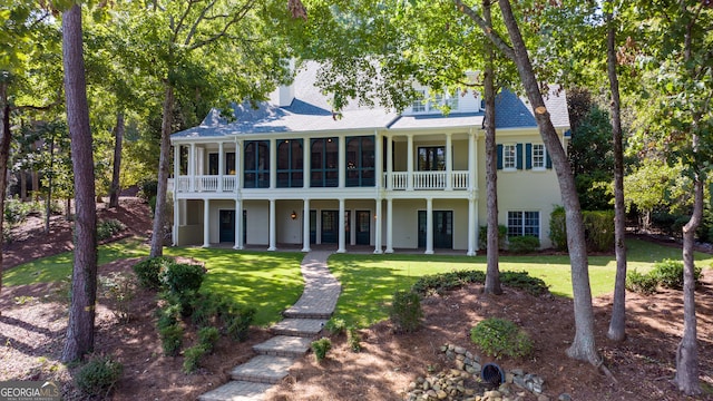 back of property featuring a balcony and a yard