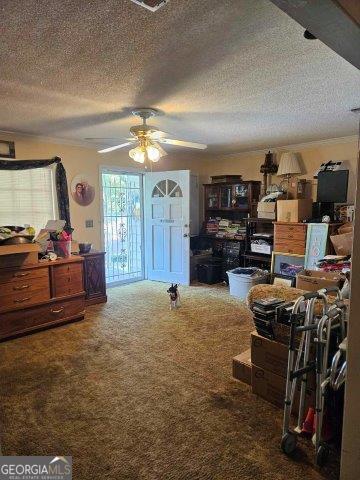 interior space with ceiling fan, a textured ceiling, and carpet flooring