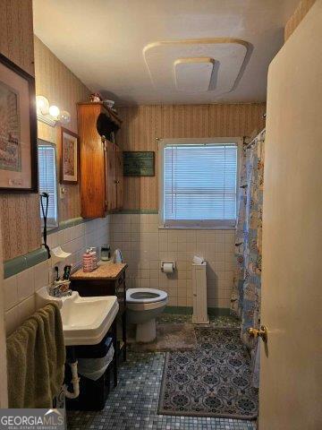 bathroom with walk in shower, tile walls, tile patterned flooring, and toilet