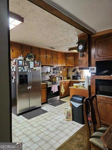 kitchen with ceiling fan, a textured ceiling, stainless steel appliances, and crown molding