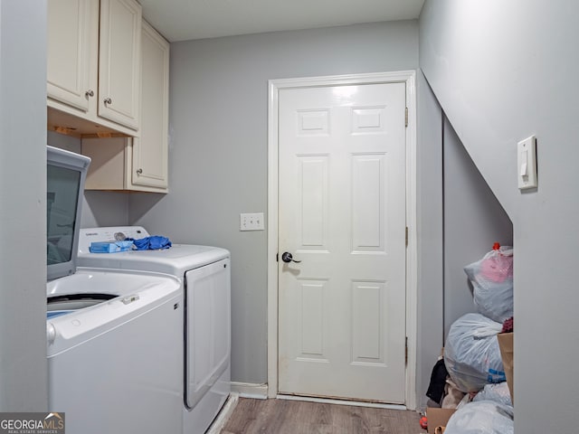 clothes washing area with cabinets, light hardwood / wood-style flooring, and washing machine and dryer