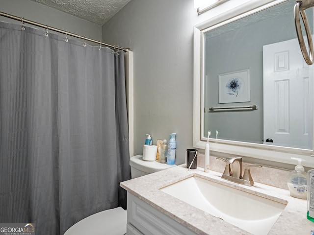 bathroom with a textured ceiling, vanity, toilet, and walk in shower