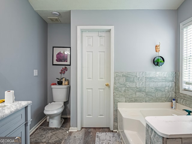 bathroom featuring wood-type flooring, vanity, toilet, and a tub