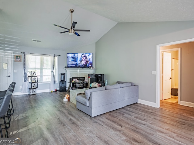 living room featuring vaulted ceiling, ceiling fan, hardwood / wood-style flooring, and a fireplace