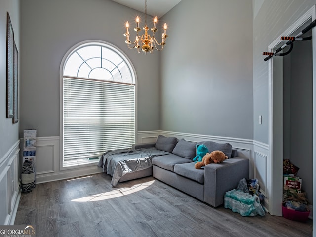 living room with an inviting chandelier, a high ceiling, and hardwood / wood-style flooring