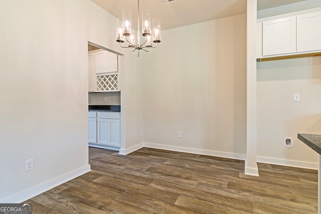 unfurnished dining area featuring dark hardwood / wood-style floors and a notable chandelier