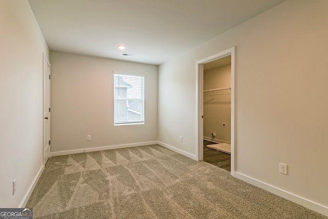 unfurnished bedroom with carpet flooring, a walk in closet, and a closet