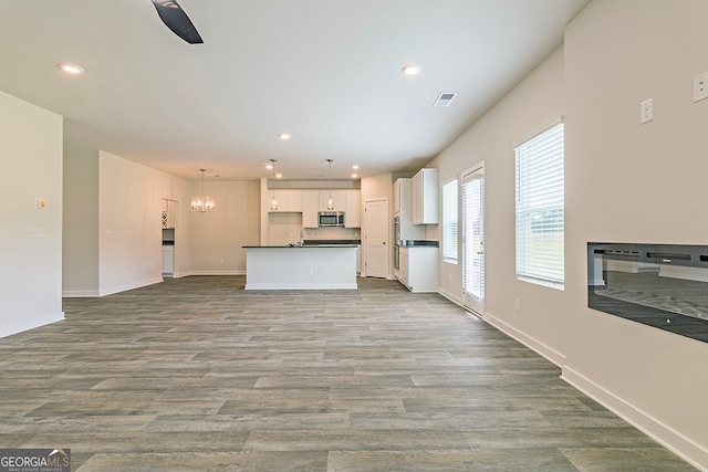 kitchen featuring hanging light fixtures, white cabinetry, appliances with stainless steel finishes, ceiling fan with notable chandelier, and light hardwood / wood-style floors