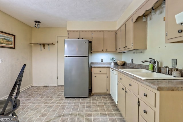 kitchen featuring a textured ceiling, stainless steel fridge, dishwasher, sink, and cream cabinetry