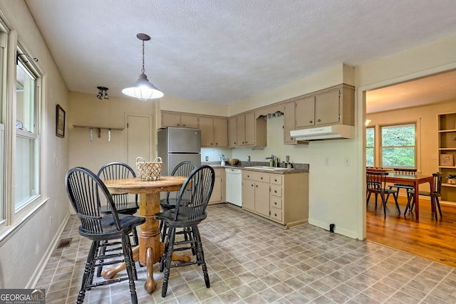 kitchen featuring stainless steel fridge, pendant lighting, sink, white dishwasher, and a textured ceiling