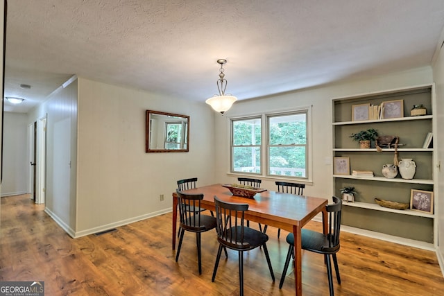 dining area with wood-type flooring and a textured ceiling