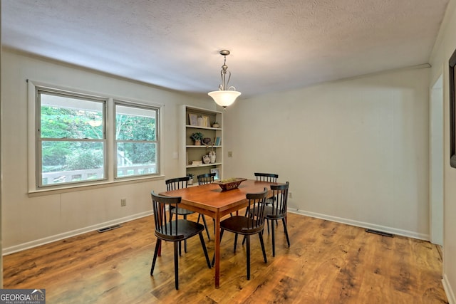 dining room with hardwood / wood-style floors and a textured ceiling