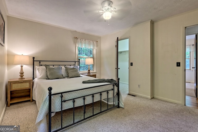 bedroom featuring light carpet, a textured ceiling, and ceiling fan