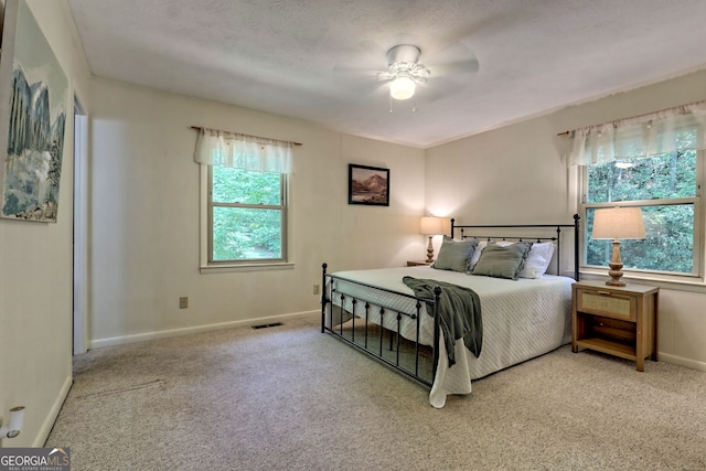 carpeted bedroom with ceiling fan and a textured ceiling