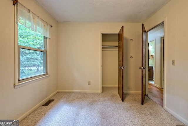 unfurnished bedroom with light colored carpet and a textured ceiling