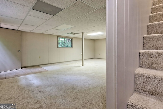 basement featuring light carpet and a paneled ceiling