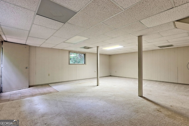 basement featuring a paneled ceiling and light colored carpet