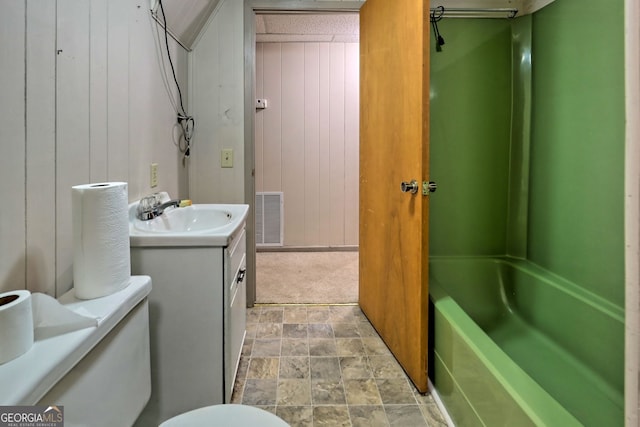 full bathroom featuring shower / bathing tub combination, wooden walls, vanity, and toilet