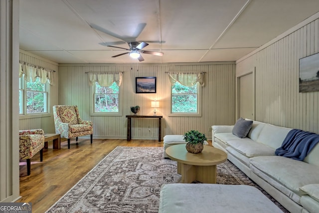 living room with a healthy amount of sunlight, wood walls, and hardwood / wood-style floors