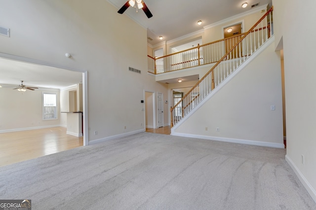 unfurnished living room with a high ceiling, ornamental molding, and ceiling fan